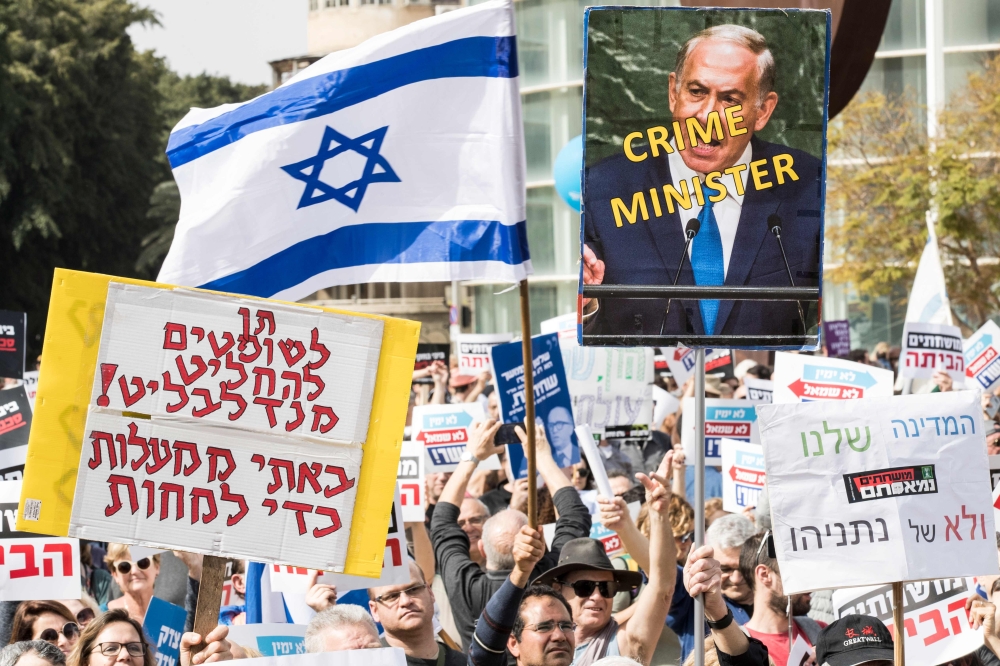 Israeli protesters raise a sign reaidng in Hebrew 