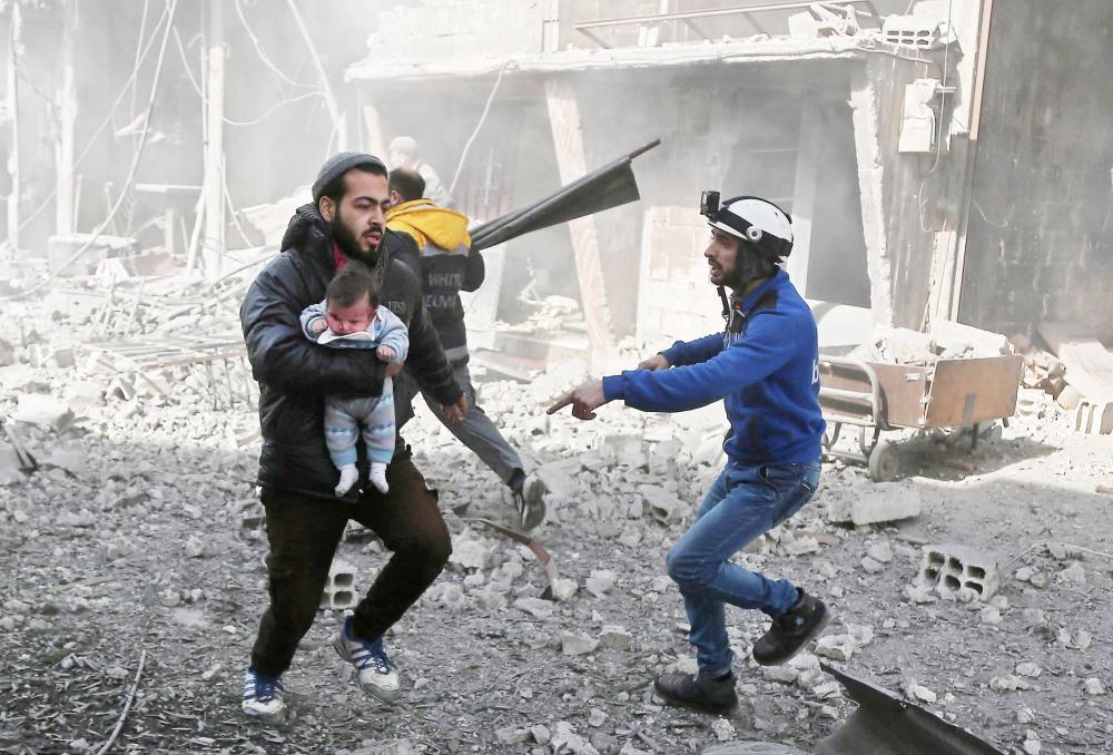 



رجل يحمل رضيعاً هرباً من قصف طيران الاسد لبلدة حمورية في الغوطة الشرقية أمس. (أ ب ف)