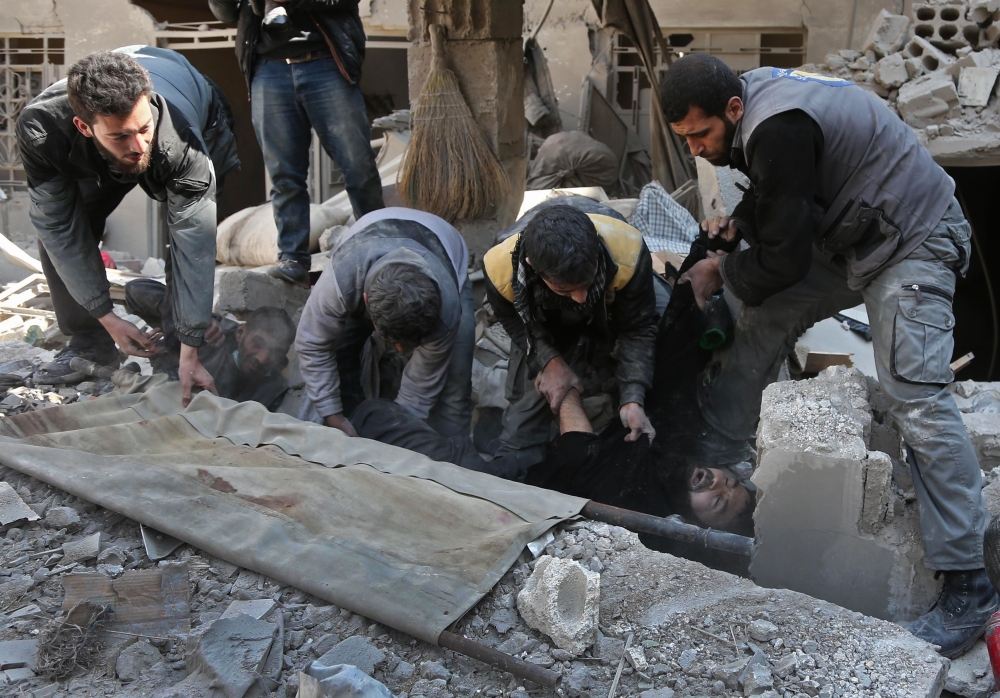 EDITORS NOTE: Graphic content / TOPSHOT - Members of a Syrian civil defence team rescue a man following a reported regime air strike in the rebel-held town of Hamouria, in the besieged Eastern Ghouta region on the outskirts of the capital Damascus on February 21, 2018. Ten civilians were killed in fresh air strikes by the Syrian regime on rebel-held Eastern Ghouta, where 270 people have died in three days of bombardment, a monitor said. / AFP / ABDULMONAM EASSA 