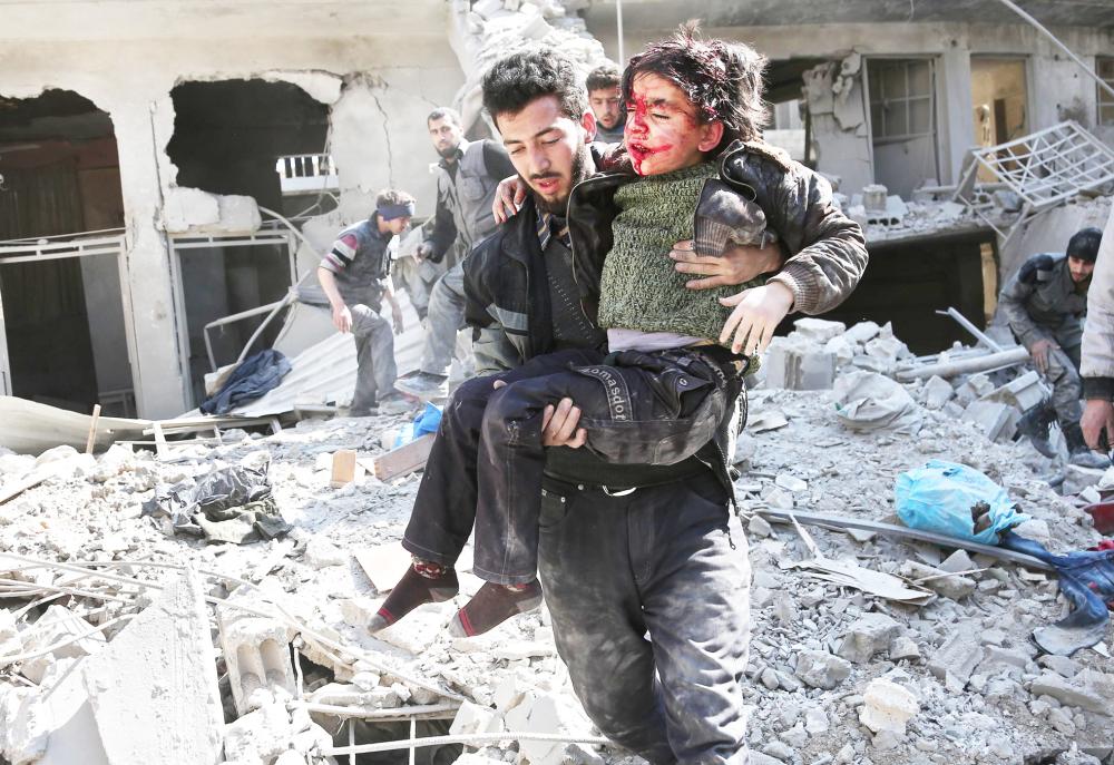 



سوري يحمل طفلة تنزف دما إثر إصابتها في قصف لنظام الأسد على بلدة حمورية في الغوطة الشرقية أمس. (أ ف ب)