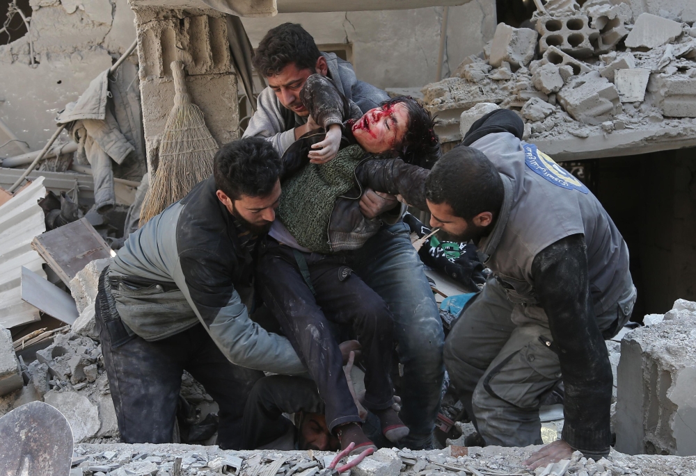 EDITORS NOTE: Graphic content / Syrians rescue a child following a reported regime air strike in the rebel-held town of Hamouria, in the besieged Eastern Ghouta region on the outskirts of the capital Damascus on February 21, 2018. / AFP / ABDULMONAM EASSA 