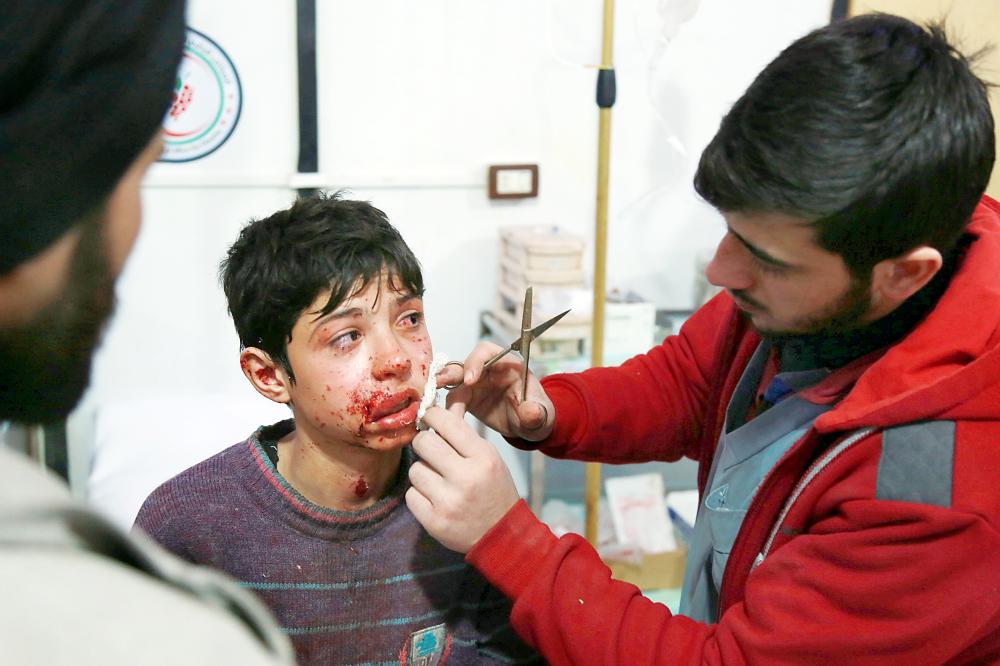 طبيب سوري يعالج طفلا أصيب في قصف نظام الأسد للغوطة. (أ ف ب)