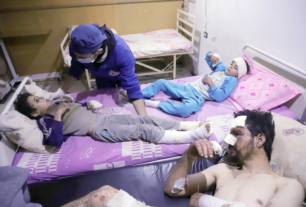 



سوريون يعالجون في مشفى بالغوطة عقب إصابتهم في غارة لنظام الأسد على المدينة أمس. (أ ف ب)