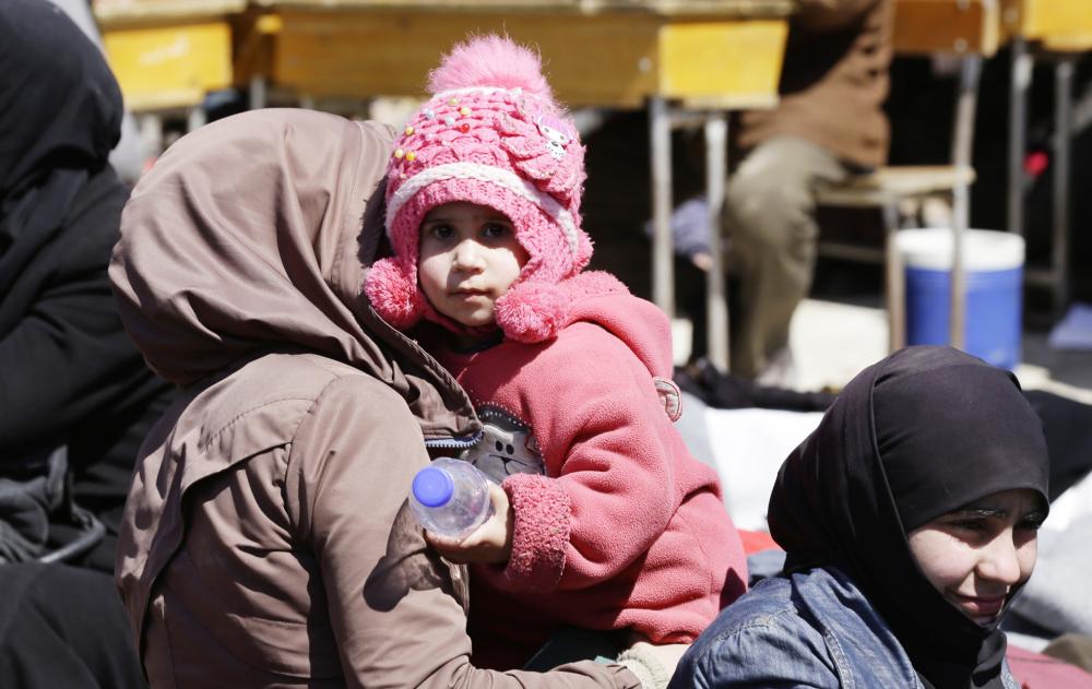 Syrian civilians evacuated from rebel-held areas in the Eastern Ghouta enclave gather at a school in the regime-controlled Adra district, on the northeastern outskirts of the capital Damascus, on March 16, 2018. Thousands of civilians poured out of Eastern Ghouta after a month-long bombardment brought the Syrian regime closer to recapturing the devastated rebel enclave outside Damascus. / AFP / LOUAI BESHARA
