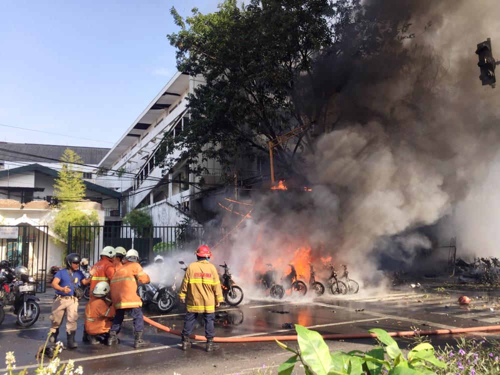 



رجال إطفاء يحاولون إخماد الحريق بعد انفجار في كنيسة في سورابايا بإندونيسيا، أمس (أ.ف.ب) 