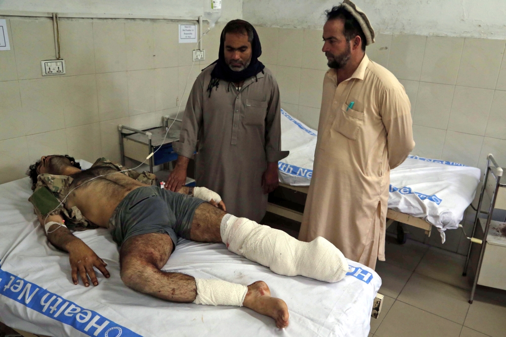 أفغان يتفقدون أحد أقاربهم الذي أصيب في تفجير ملعب في جلال أباد أمس.(إ.ب.أ)