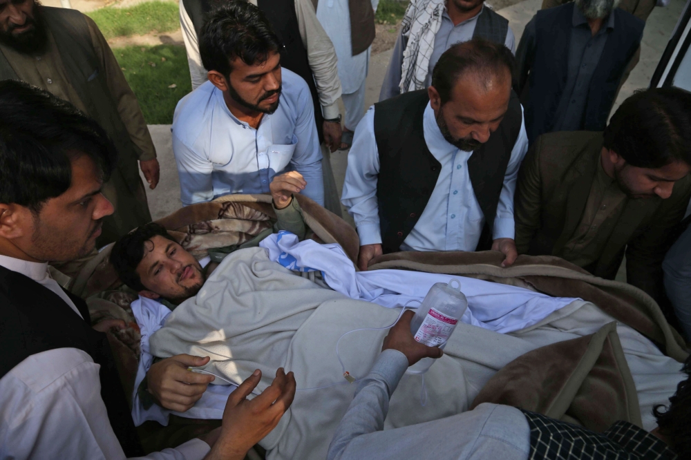 أفغان ينقلون أحد جرحى أنفجار ملعب في جلال أباد أمس.(إ.ب.أ)