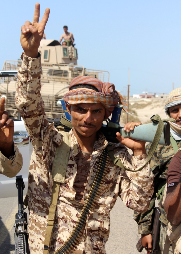 (FILES) A file photo taken on December 10, 2017 shows a Yemeni fighter loyal to the Saudi-backed Yemeni president flashing the victory gesture as he walks on a road leading to the town of Khokha which was retaken from Shiite-Huthi rebels, about 120 kilometres south of the Huthi rebel-held Red Sea port of Hodeida.  / AFP / SALEH AL-OBEIDI
