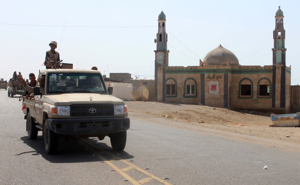 (FILES) A file photo taken on December 10, 2017 shows Yemeni fighters loyal to the Saudi-backed Yemeni president riding in the back of a pickup truck past a mosque, on a road leading to the town of Khokha which was retaken from Shiite-Huthi rebels, about 120 kilometres south of the Huthi rebel-held Red Sea port of Hodeida.  / AFP / SALEH AL-OBEIDI
