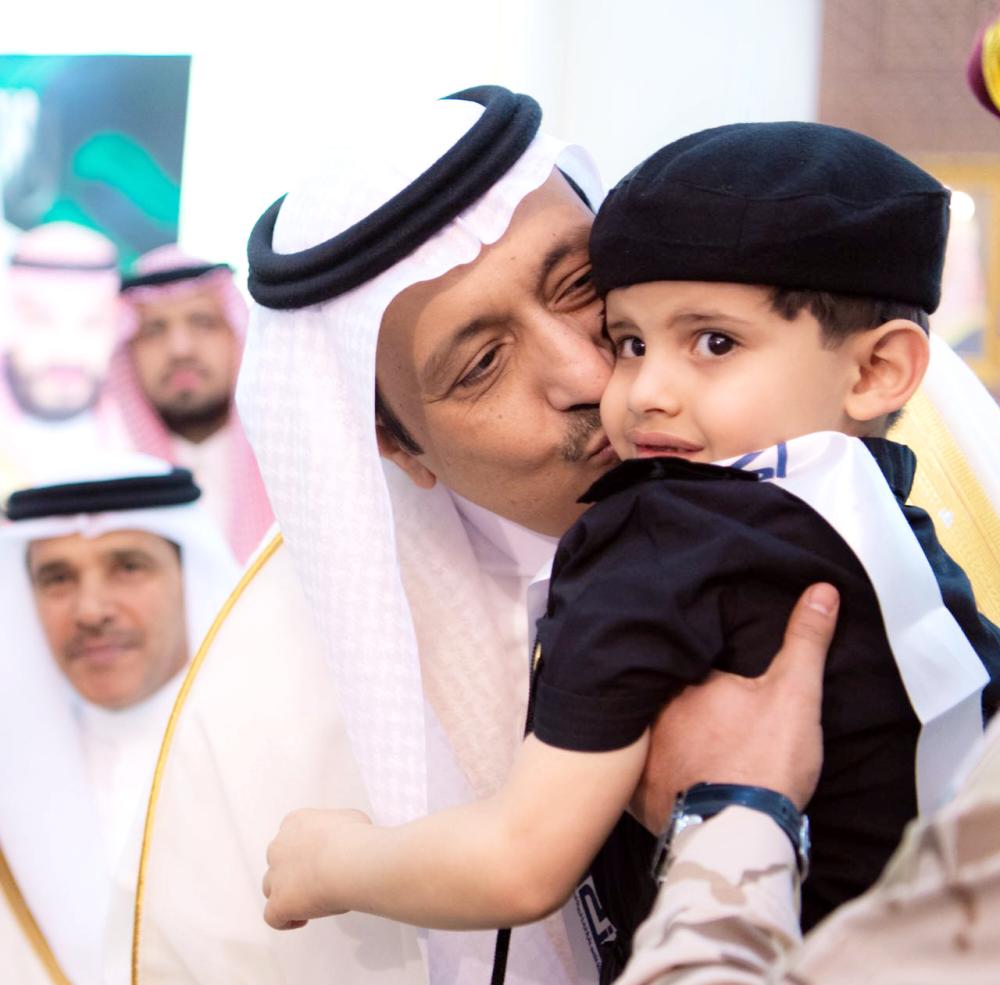 



 الأمير حسام بن سعود مقبلاً أحد أبناء شهداء الواجب.