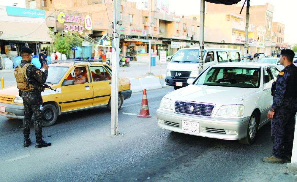 



رجال الشرطة العراقية يتفقدون المركبات عند نقطة تفتيش في بغداد، أمس الأول. (رويترز) 