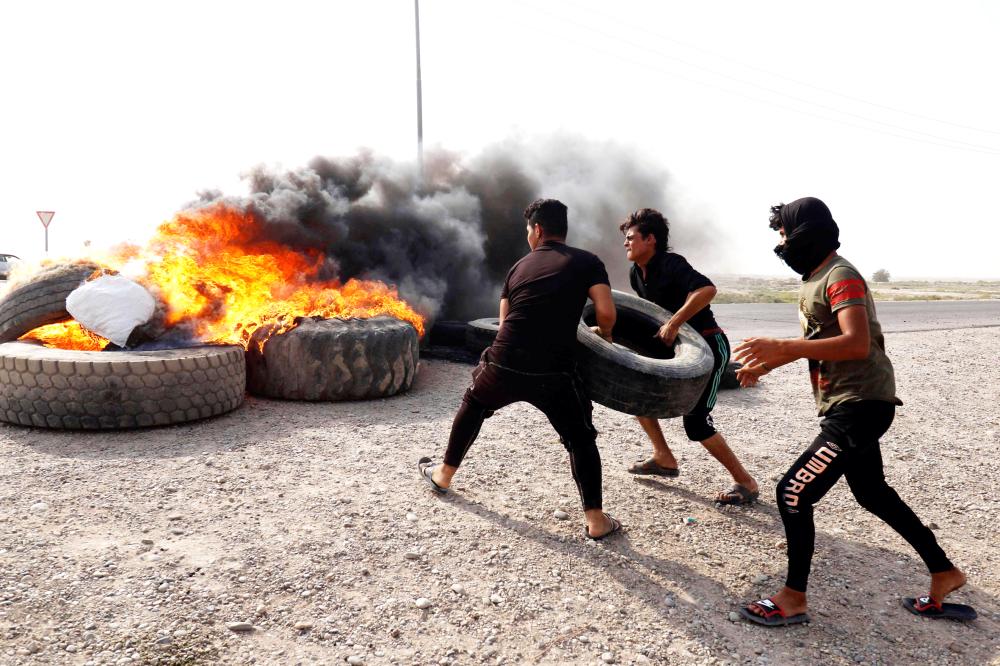 Iraqi protestors burn tyres during a gathering northwest of the southern city Basra on July 17, 2018, during a demonstration against unemployment and a lack of basic services.  / AFP / Haidar MOHAMMED ALI
