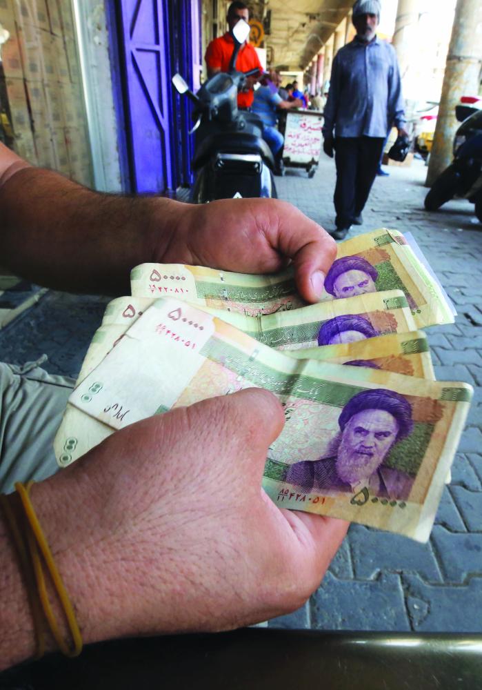An Iraqi peddler holds in hand Iranian currency for sell in the capital Baghdad, on August 9, 2018. Caught in the crossfire between its key allies Tehran and Washington, Iraq's economy could suffer the heaviest collateral damage from the US reimposing sanctions against Iran. / AFP / AHMAD AL-RUBAYE
