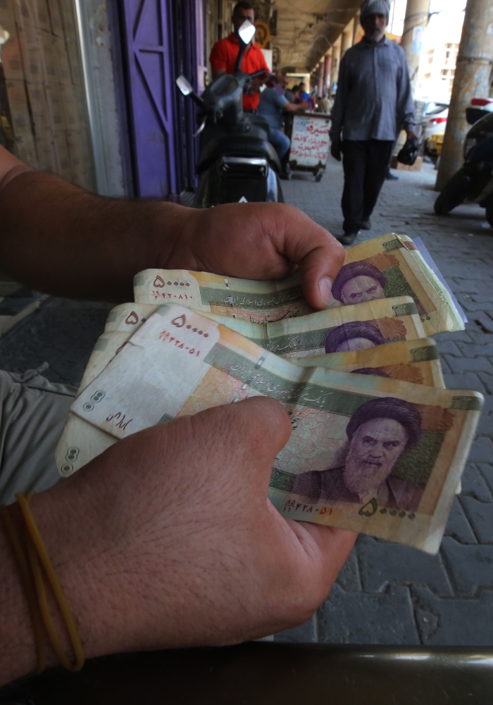 An Iraqi peddler holds in hand Iranian currency for sell in the capital Baghdad, on August 9, 2018. Caught in the crossfire between its key allies Tehran and Washington, Iraq's economy could suffer the heaviest collateral damage from the US reimposing sanctions against Iran. / AFP / AHMAD AL-RUBAYE
