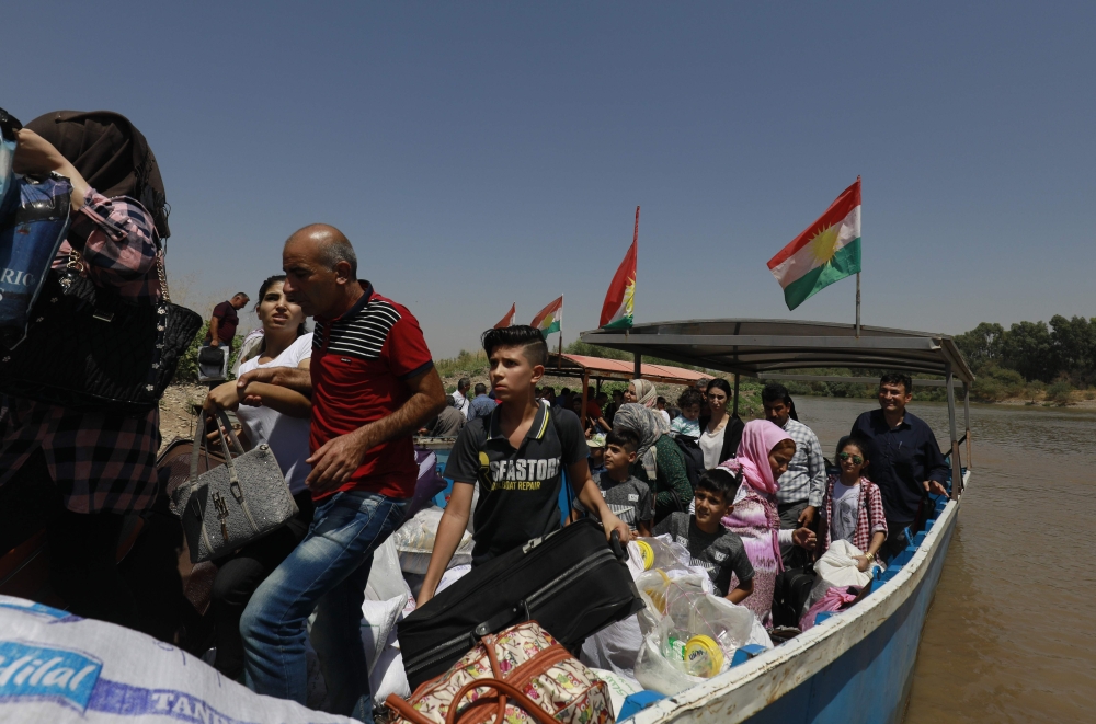 People from Iraqi Kurdistan cross the Tigris river at the Semalka crossing to visit family on the Syrian side on August 19, 2018, ahead of the Eid al-Adha Muslim holiday. 
 Muslims across the world will celebrate the annual festival of Eid al-Adha, or the Festival of Sacrifice, which marks the end of the Hajj pilgrimage to Mecca and in commemoration of Prophet Abraham's readiness to sacrifice his son to show obedience to God. / AFP / Delil souleiman
