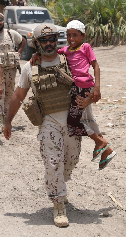 جندي من القوات الإماراتية يقوم بإسعاف أطفال أستهدفهم الحوثيون بالصواريخ.(وام)