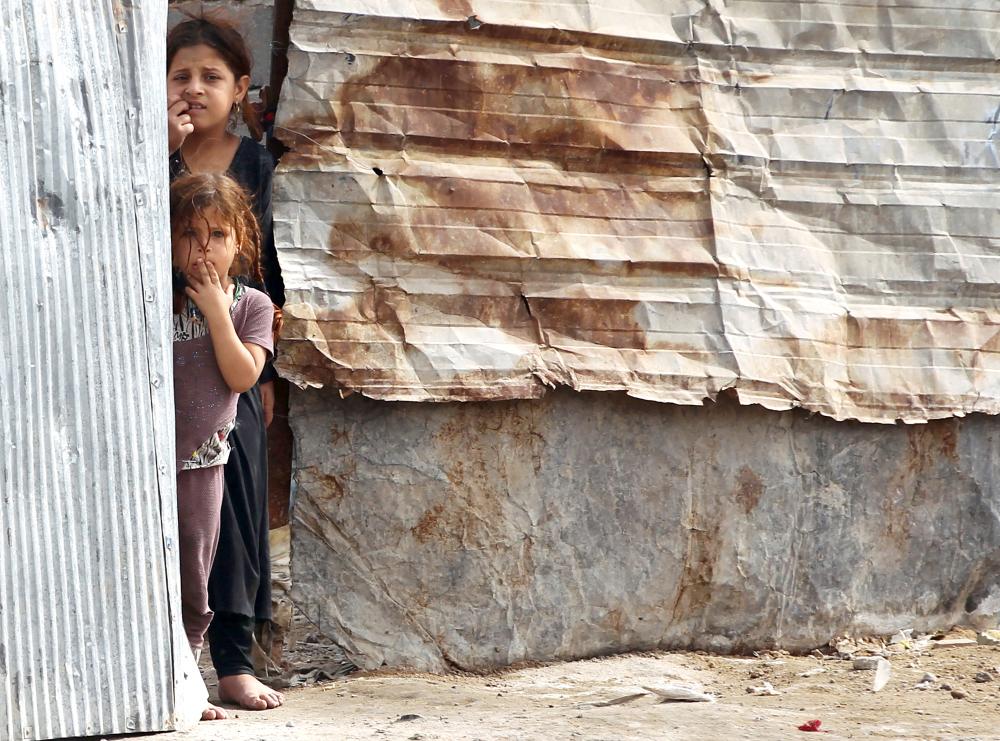 



 طفلتان عراقيتان تقفان قرب مدخل منزلهما في حي مدينة الصدر في بغداد أمس. (أ ف ب)