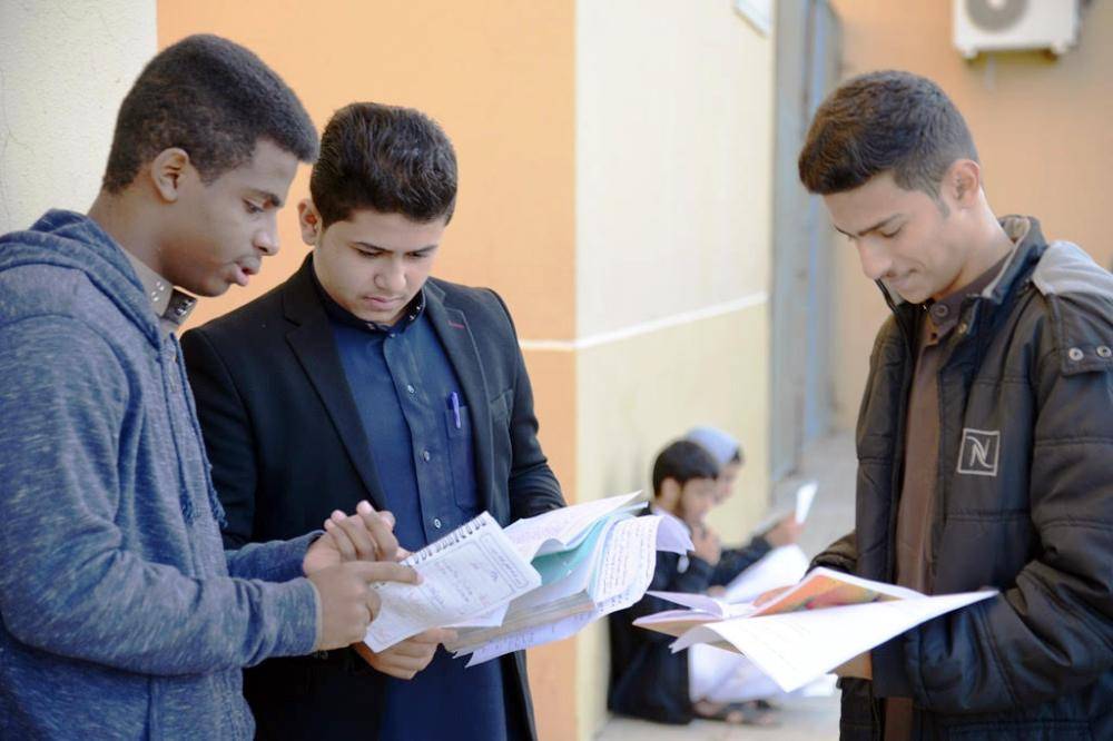 طلاب يتصفحون مادة اختبارهم الأول قبل دخولهم القاعة. (تصوير: يحيى الفيفي yahyafifi4324@)