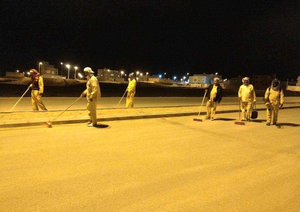 عمالة بلدية الوجه يقومون بنظافة أحد شوارع المحافظة ليلاً