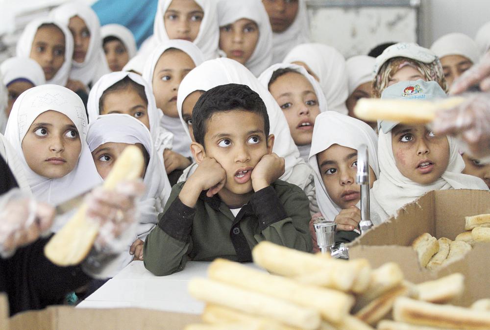 تلاميذ يحصلون على وجبة طعام توزعها جمعية خيرية محلية على مدرسة في صنعاء أمس الأول. (رويترز)