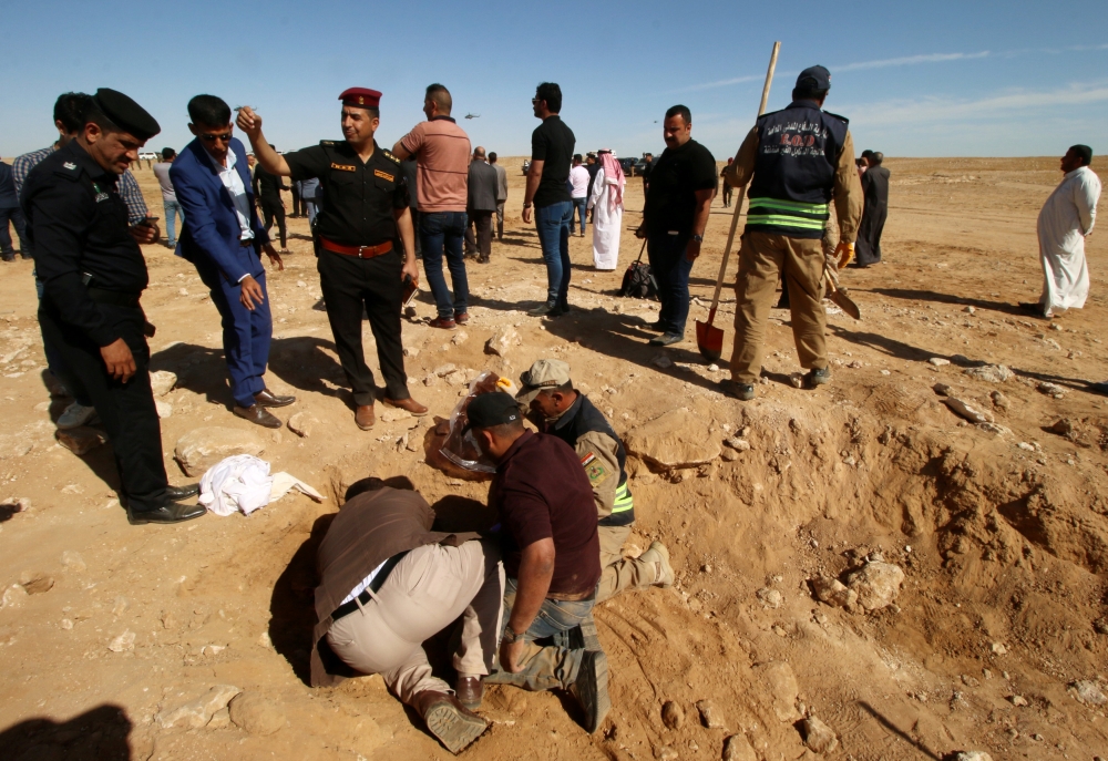 Iraqi members of the Civil Defense and Kurdish men examine an unearthed mass grave of Kurds in west of the city of Samawa, Iraq April 14, 2019. REUTERS/Essam al-Sudani