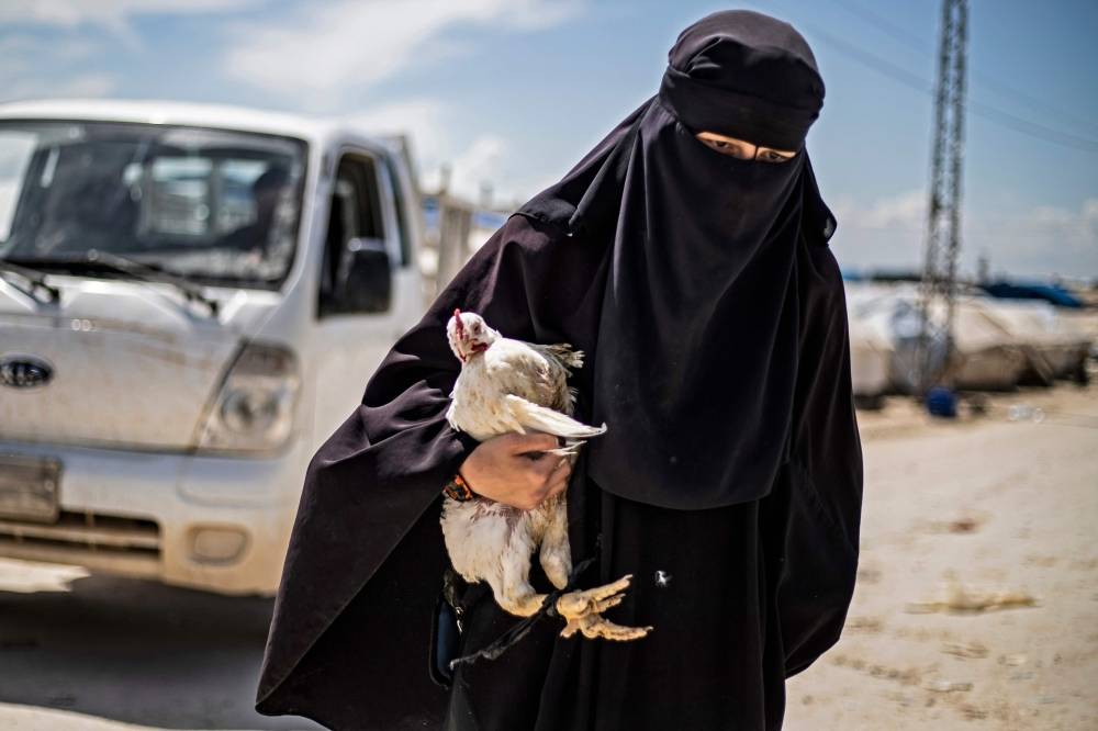 A woman displaced from Syria's eastern Deir Ezzor province, carries a hen as she walks in al-Hol camp for displaced people, in al-Hasakeh governorate in northeastern Syria on April 18, 2019. Dislodged in a final offensive by a Kurdish-led ground force and coalition air strikes, thousands of wives and children of IS fighters have flooded in from a string of Syrian villages south of the al-Hol camp in recent months.
Among the hordes of Syrians and Iraqis, some 9,000 foreigners are held in a fenced section of the encampment, under the watch of Kurdish forces. / AFP / Delil SOULEIMAN
