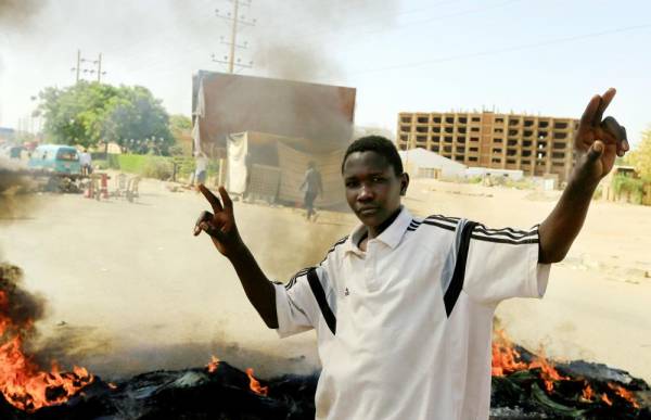 



متظاهر سوداني يرفع علامة النصر أمام إطارات محترقة في طريق يربط الخرطوم بحري والخرطوم. (رويترز)
