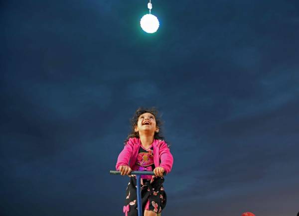 TOPSHOT - A Syrian girl smiles at an amusement park near a IDP camp for displaced persons in the area of Afrin, along Syria's northern border with Turkey on June 5, 2019 during Eid al-Fitr which masks the end of the Muslim holy fasting month of Ramadan. / AFP / Rami al SAYED
