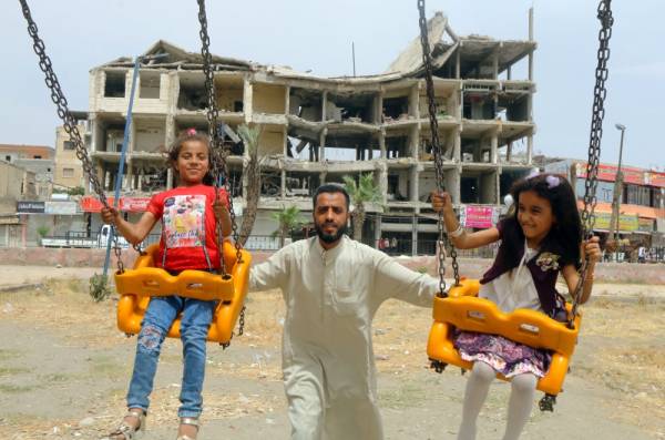 Girls ride on swings near a damaged building during the first day of the Muslim holiday of Eid al-Fitr in Raqqa, Syria, June 5, 2019. REUTERS/Aboud Hamam