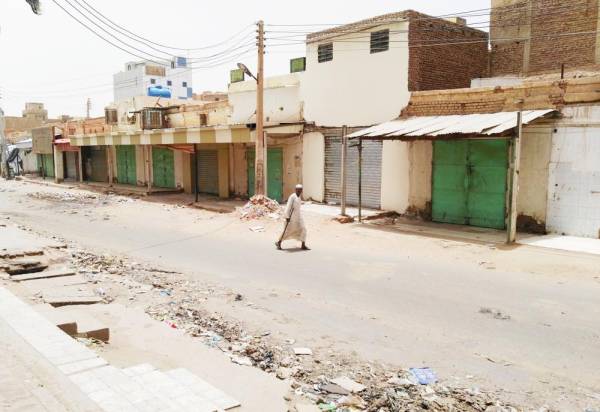 مواطن سوداني يتجول وحيداً أمام محلات تجارية مغلقة في الخرطوم تجاوباً مع دعوة المعارضة للعصيان المدني أمس. (أ.ف.ب)