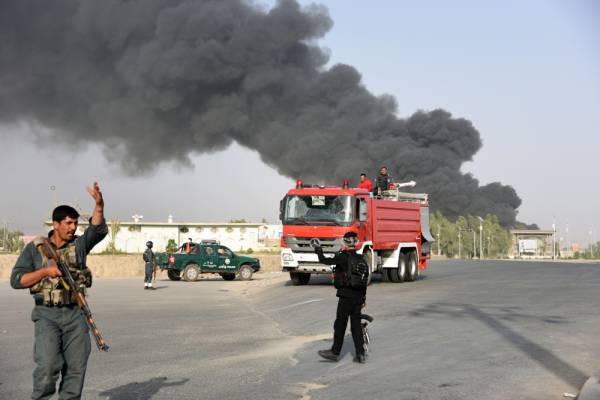 Afghan policemen arrive near a site of car bomb attack as smoke rises from the Police headquarters in Kandahar province on July 18, 2019. / AFP / JAVED TANVEER 