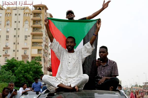 Sudanese demonstraters wave their national flag as they celebrate in Khartoum early on August 3, 2019, after Sudan's ruling generals and protest leaders reached a «full agreement» on the constitutional declaration. The document is complementary to a power-sharing deal signed on July 17 that aims to form a joint civilian-military ruling body which will oversee the formation of a transitional civilian government and parliament to govern for a three-year transition period. / AFP / Ebrahim HAMID
