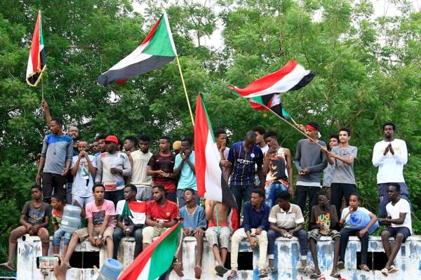 Sudanese demonstraters wave their national flag as they celebrate in Khartoum early on August 3, 2019, after Sudan's ruling generals and protest leaders reached a «full agreement» on the constitutional declaration. The document is complementary to a power-sharing deal signed on July 17 that aims to form a joint civilian-military ruling body which will oversee the formation of a transitional civilian government and parliament to govern for a three-year transition period. / AFP / Ebrahim HAMID
