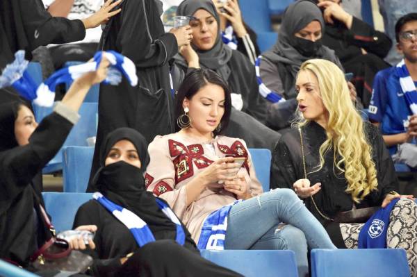 A female supporter of al-Hilal uses a cell phone as she sits in the stands during the AFC Champions League quarter-finals football match between Saudi Arabia's  Al-Ittihad and Al-Hilal at the King Saud University Stadium in Riyadh on September 17, 2019. / AFP / Fayez Nureldine
