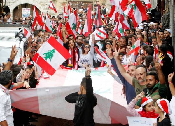 



متظاهرون يؤشرون بعلامة النصر ويرفعون الأعلام اللبنانية خلال احتجاجات حاشدة مناهضة في بلدة حاصبيا أمس. (رويترز)