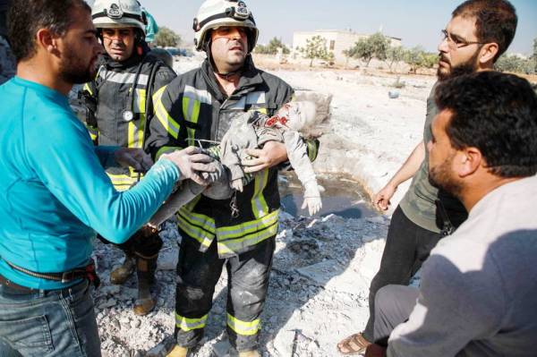 



أحد أفراد الدفاع المدني السوري يحمل جثة فتاة قُتلت في غارة جوية على قرية السحارة السورية في ريف حلب، أمس. (أ.ف.ب)