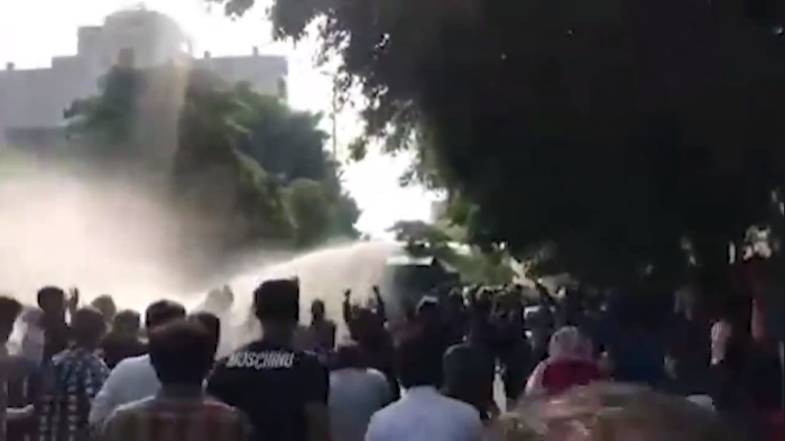 متظاهرون إيرانيون يواجهون خراطيم المياه.