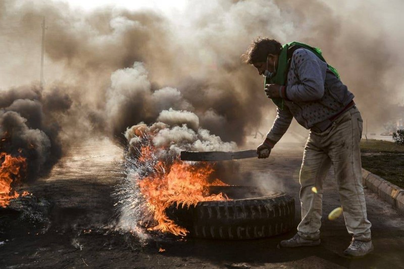 متظاهر عراقي يشعل النار في إطارات لقطع الطرق في النجف أمس.(وكالات)