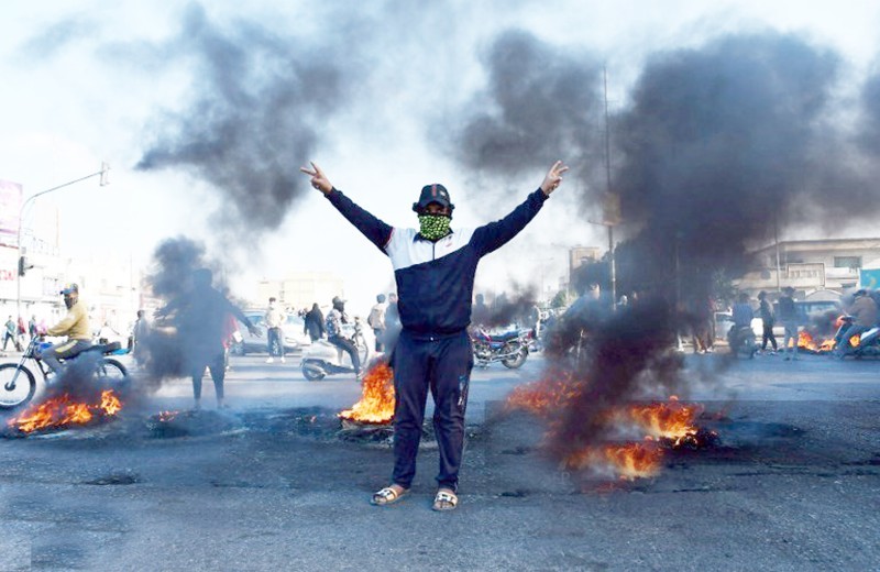 



 عراقي يؤشر بعلامة النصر أمام إطارات محترقة لإغلاق طريق خلال مظاهرة ضد علاوي في مدينة الناصرية جنوب العراق أمس. (وكالات)