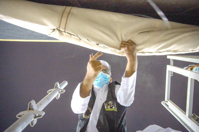 



أحد منسوبي مصنع كسوة الكعبة يباشر مهمة رفع الجزء السفلي من الكسوة.