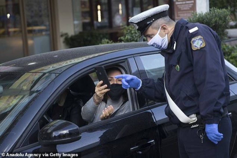 يونانية تطلع شرطياً على هاتفها لتأكيد حصولها على إذن حكومي بمغادرة منزلها على رغم الإغلاق.