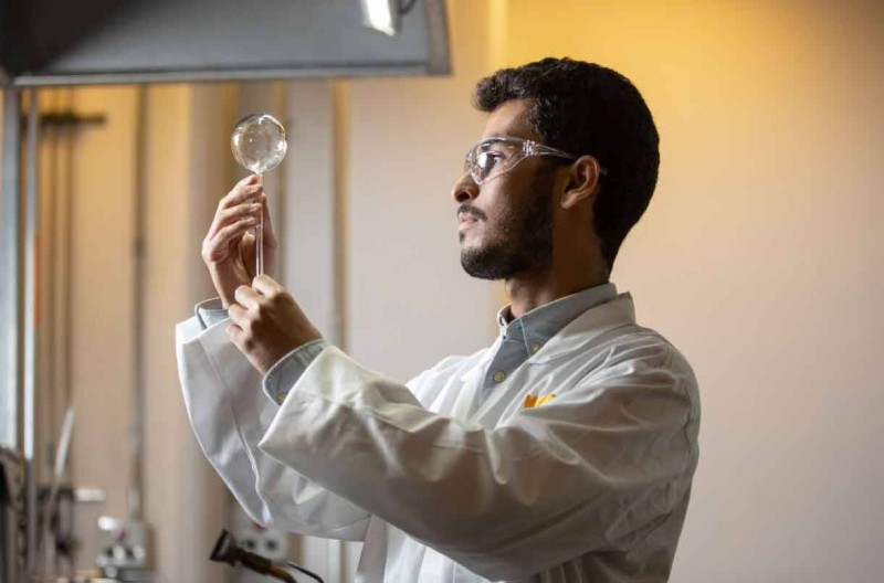 محمد العمري يتفقد قطعة من الأواني الزجاجية في ورشة نفخ الزجاج في الجامعة.