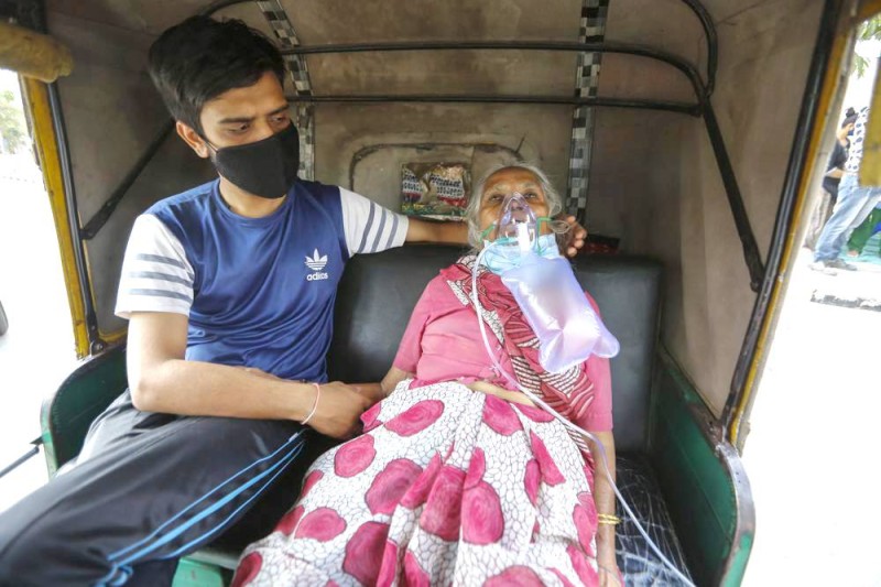 



مريضة بكوفيد تنتظر على متن عربة ريكشو لحين إيجاد سرير لتنويمها في أحمد آباد.