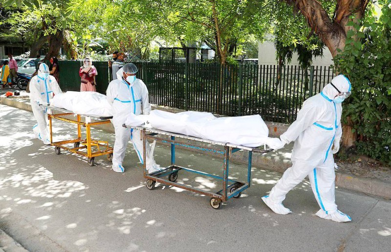 عمال صحيون ينقلون جثامين متوفين بكوفيد من أحد مستشفيات نيودلهي.