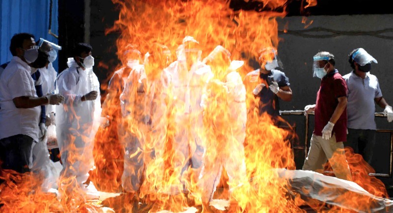 



أقارب متوفى بكوفيد يراقبون حرق جثمانه في محرقة في العاصمة نيودلهي.