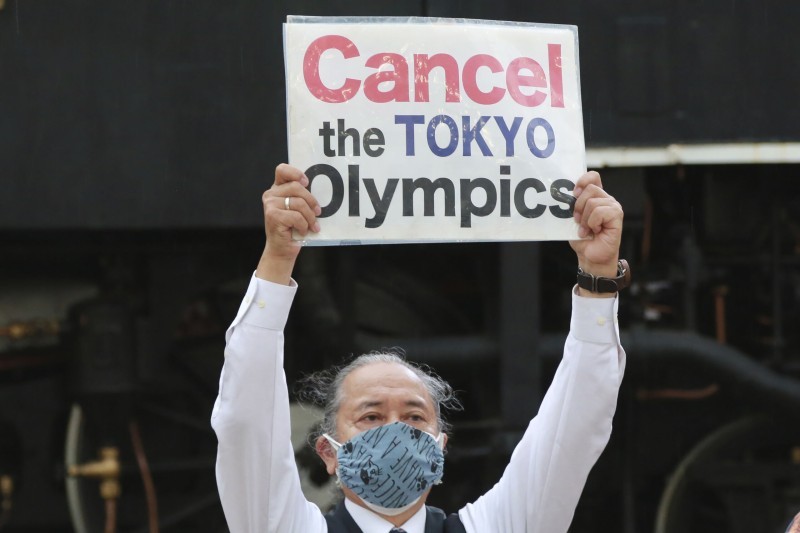 أعضاء المجموعة المناهضة للألعاب الأولمبية يرفعون لافتات خلال مسيرة احتجاجية وسط تفشي كوفيد-19 في طوكيو.