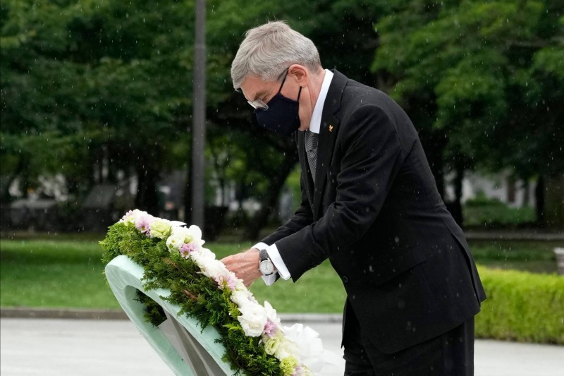 رئيس اللجنة الأولمبية الدولية توماس باخ يضع إكليلا من الزهور خلال زيارته نصب هيروشيما التذكاري يوم 16 يوليو. (AFP)