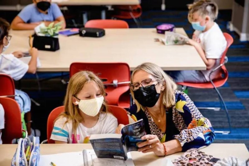 



معلمة تساعد طفلة بمدرسة أمريكية في أتون تفشي دلتا. (وكالات)