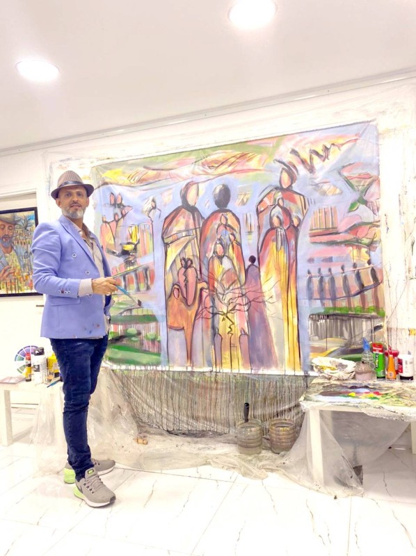 الفنان التشكيلي خالد بكران يضع اللمسات الأخيرة على لوحته «أنا الإنسان» التي سيشارك بها في معرض الرسم الحر بأحد مراكز الفنون بجدة. (عكاظ)