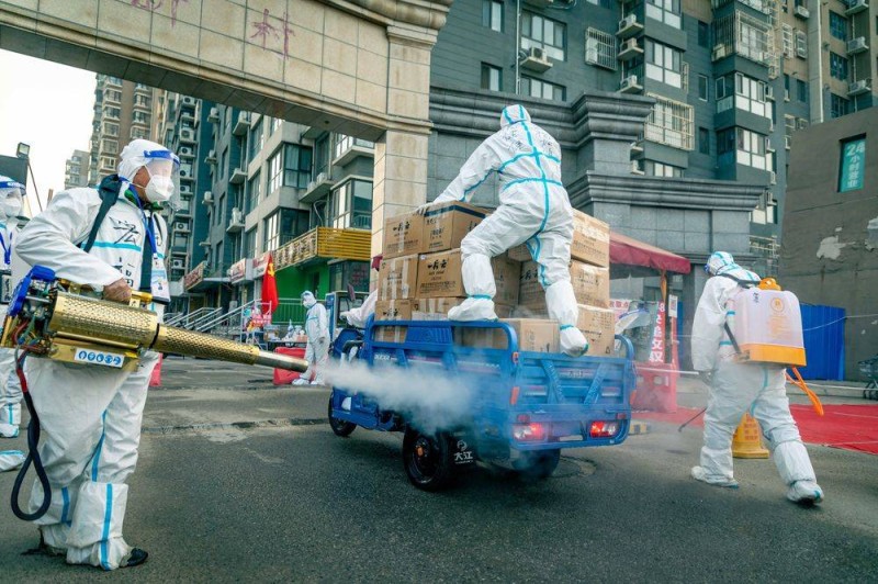 عمال صينيون يقومون بتعقيم إمدادات البضائع في أحد أحياء بكين. (وكالات)